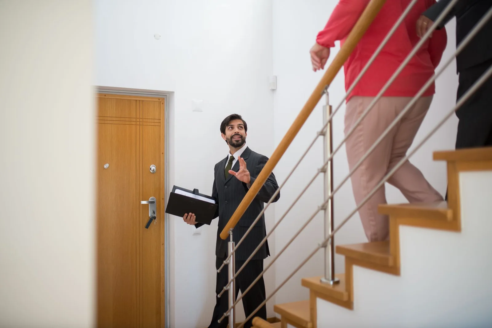 Courtier immobilier en complet qui fait visiter une maison à vendre à des acheteurs.