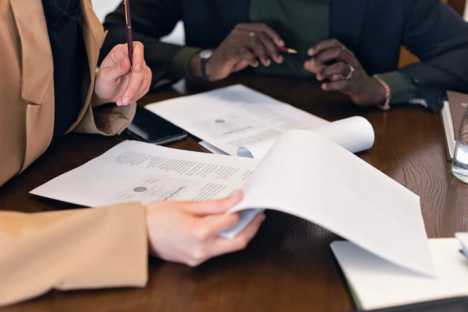 Mains qui examinent des documents sur une table pendant une rencontre.